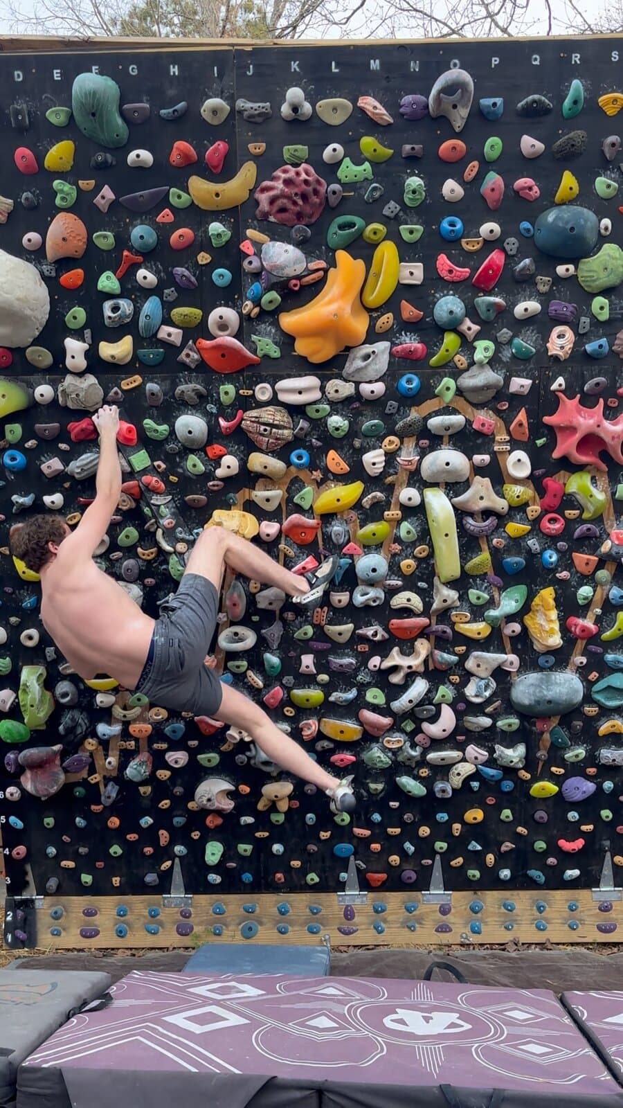 A climber swinging into a big move on the backyard wall