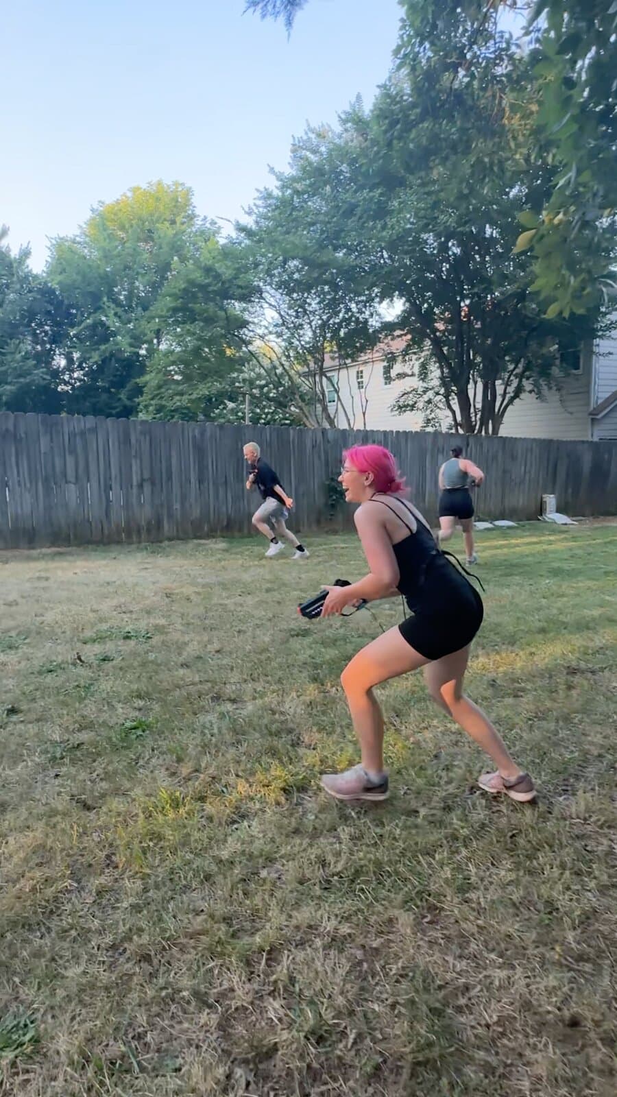 A contestant running across a backyard lawn in a low crouch