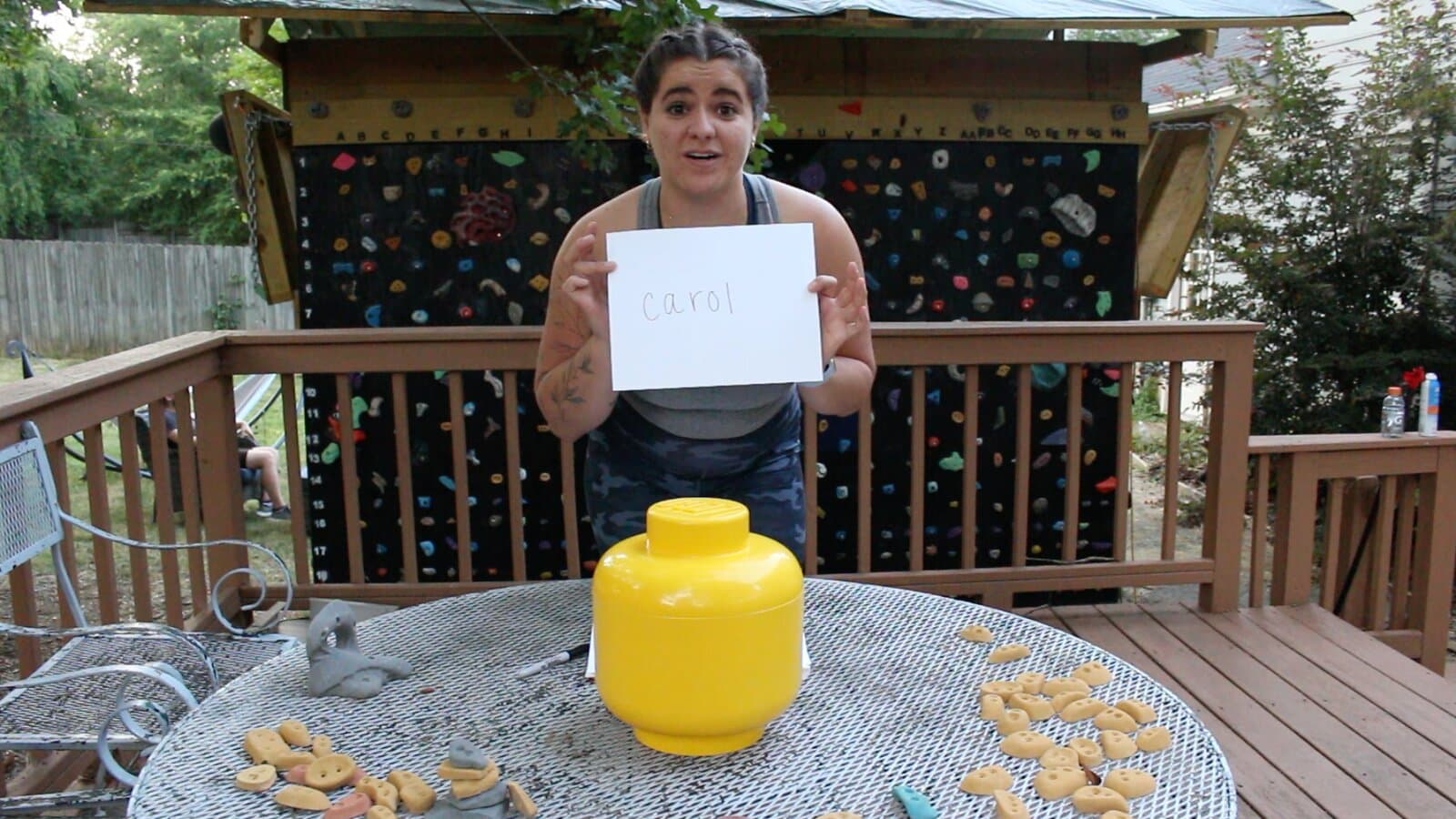 A contestant holding up a written vote behind the yellow LEGO-head urn